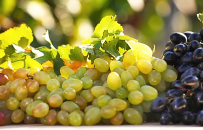 Photo of Fresh ripe juicy grapes on table against blurred background