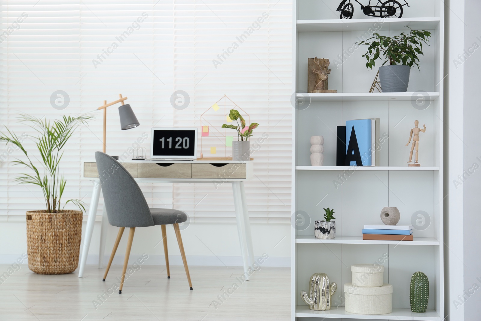 Photo of Cozy workspace with laptop, desk and comfortable chair at home. Stylish interior design