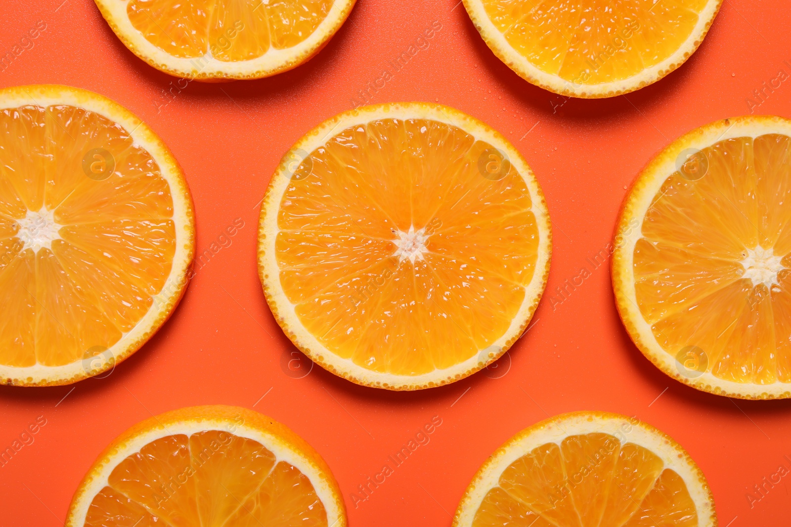 Photo of Slices of juicy orange on terracotta background, flat lay