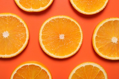 Photo of Slices of juicy orange on terracotta background, flat lay