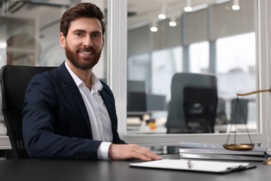 Photo of Portrait of smiling lawyer at table in office. Space for text