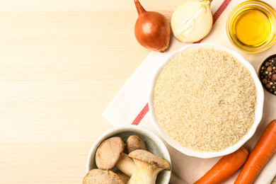 Photo of Flat lay composition with different ingredients on wooden table, space for text. Risotto recipe