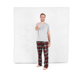 Photo of Young man with comfortable mattress isolated on white