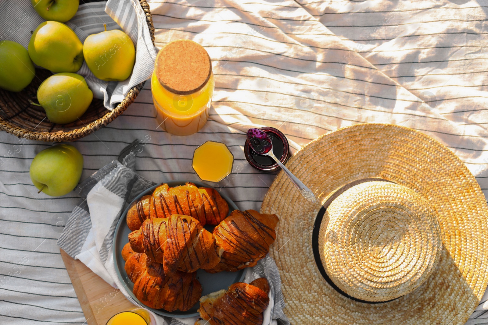 Photo of Delicious food and juice on striped blanket outdoors, flat lay. Picnic season