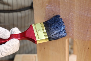 Photo of Man varnishing wooden step stool, closeup view