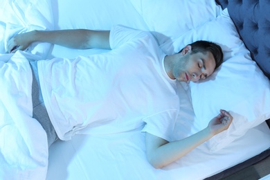 Photo of Young man sleeping in bed at night, top view