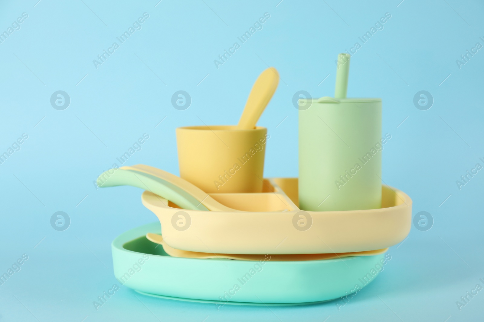 Photo of Set of plastic dishware on light blue background. Serving baby food