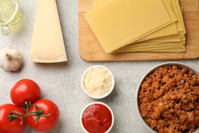 Flat lay composition with products for cooking lasagna on grey textured table