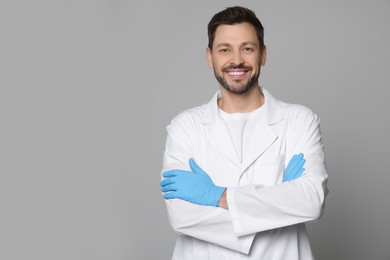 Photo of Doctor or medical assistant (male nurse) in uniform on light grey background. Space for text
