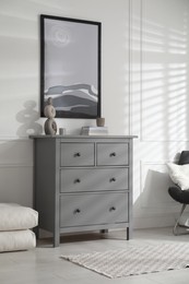 Stylish room interior with grey chest of drawers and beautiful picture