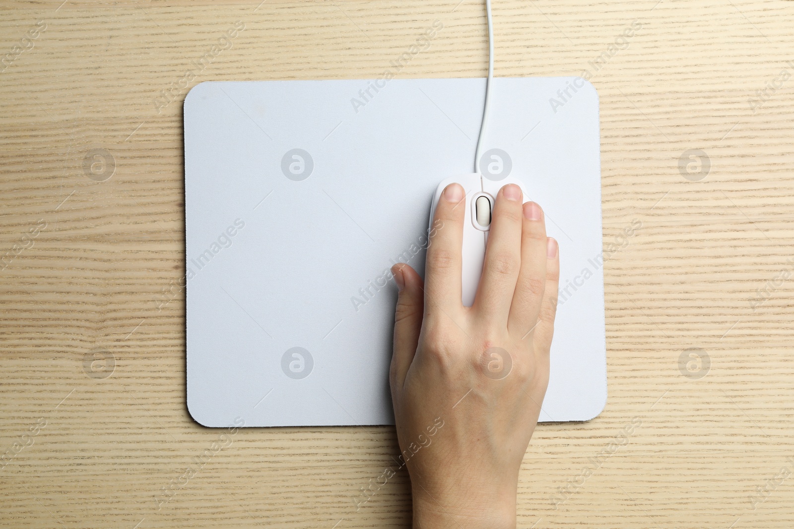 Photo of Woman using wired computer mouse on wooden table, top view. Space for text