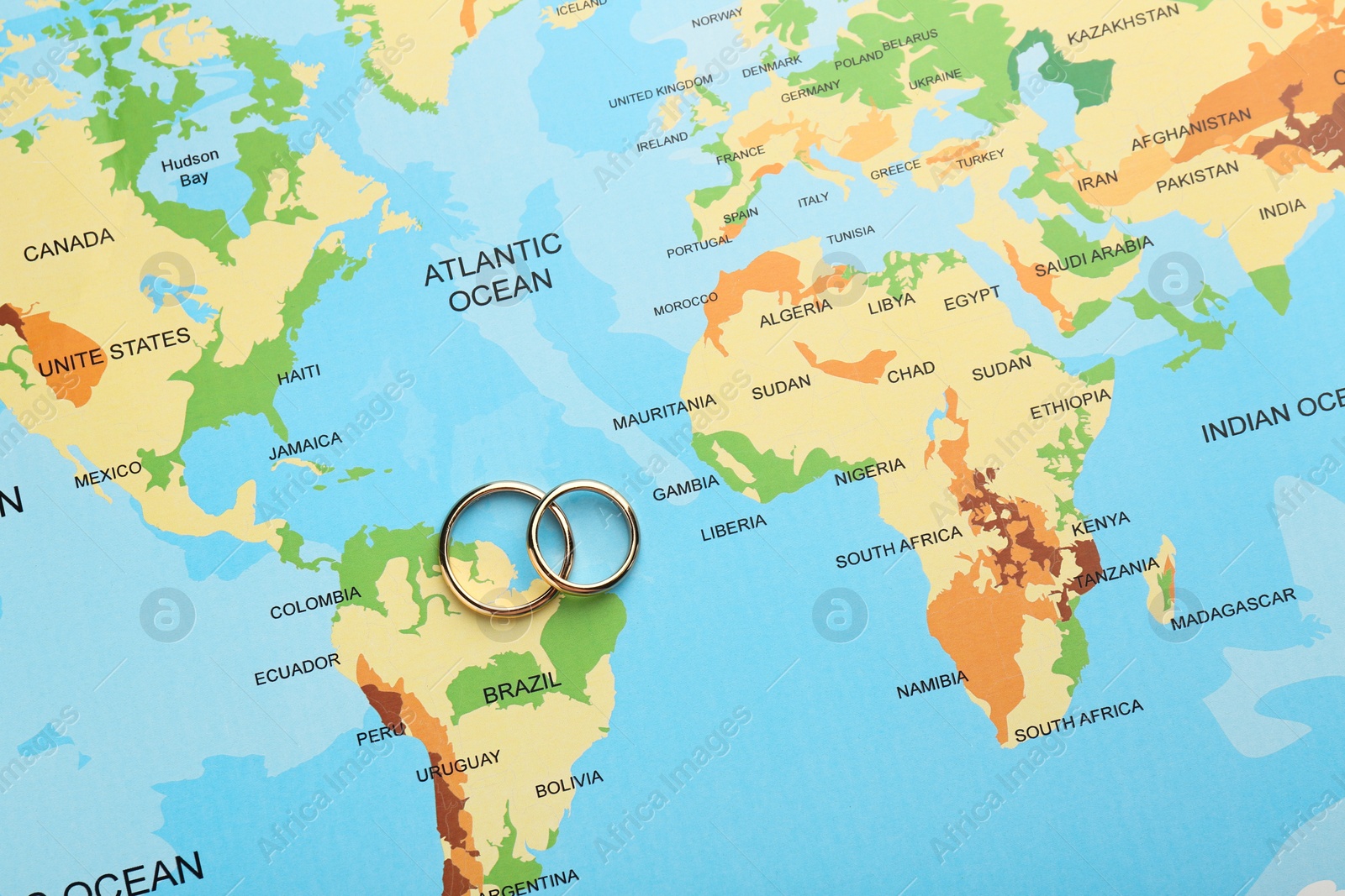 Photo of Honeymoon concept. Two golden rings on world map, top view
