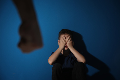 Man threatens his son on blue background. Domestic violence concept