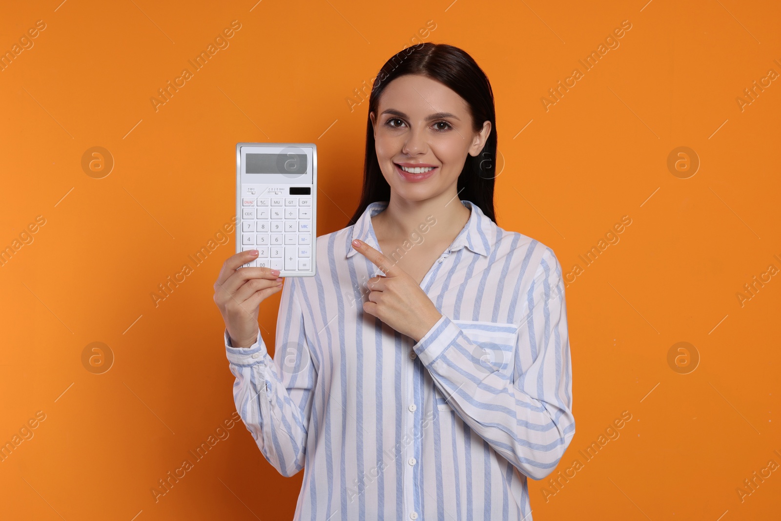 Photo of Smiling accountant with calculator on orange background