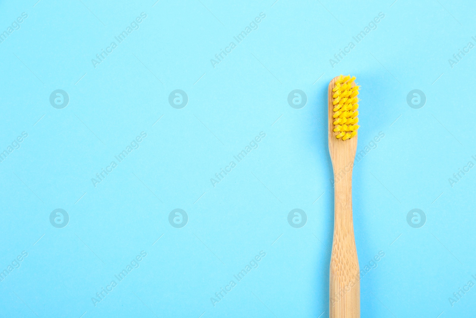 Photo of Toothbrush made of bamboo on light blue background, top view. Space for text