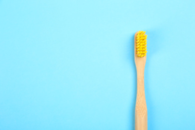 Toothbrush made of bamboo on light blue background, top view. Space for text