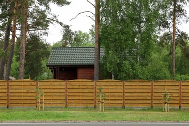 Photo of Modern building with green roof behind wooden fence on spring day