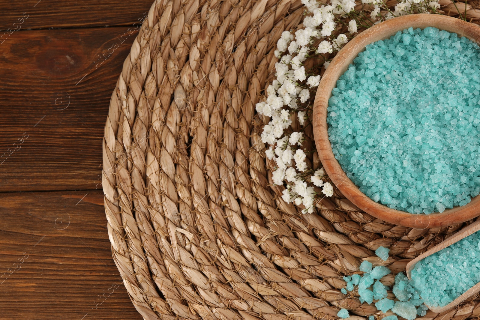 Photo of Bowl and spoon with sea salt, beautiful flowers on wooden table, flat lay. Space for text