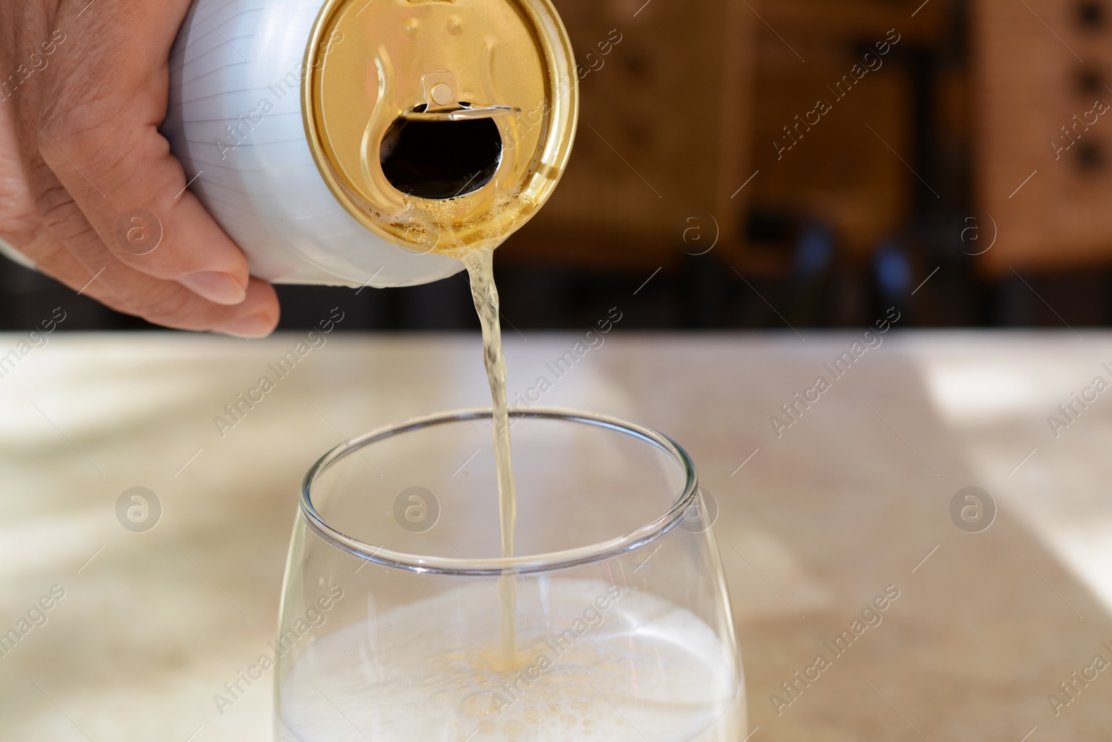 Photo of Man pouring beer from can into glass at table, closeup. Space for text