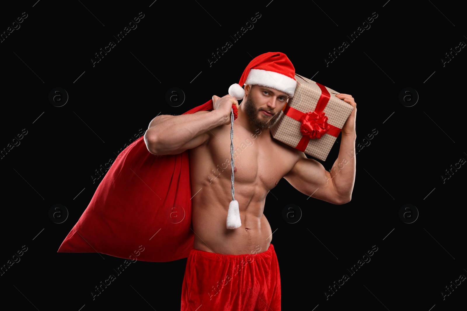 Photo of Attractive young man with muscular body holding bag and Christmas gift box on black background