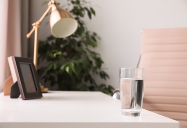 Glass of fresh water on table indoors. Space for text