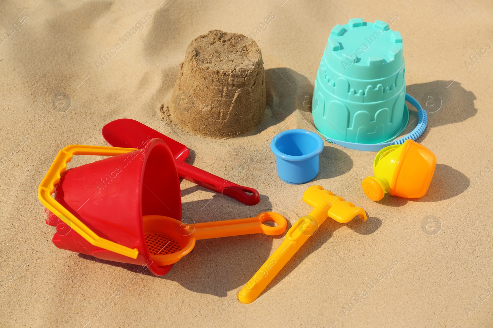 Photo of Set of plastic beach toys on sand. Outdoor play