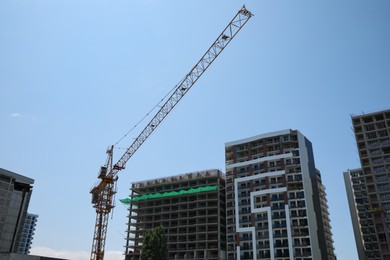 Construction site with tower crane near unfinished building, low angle view