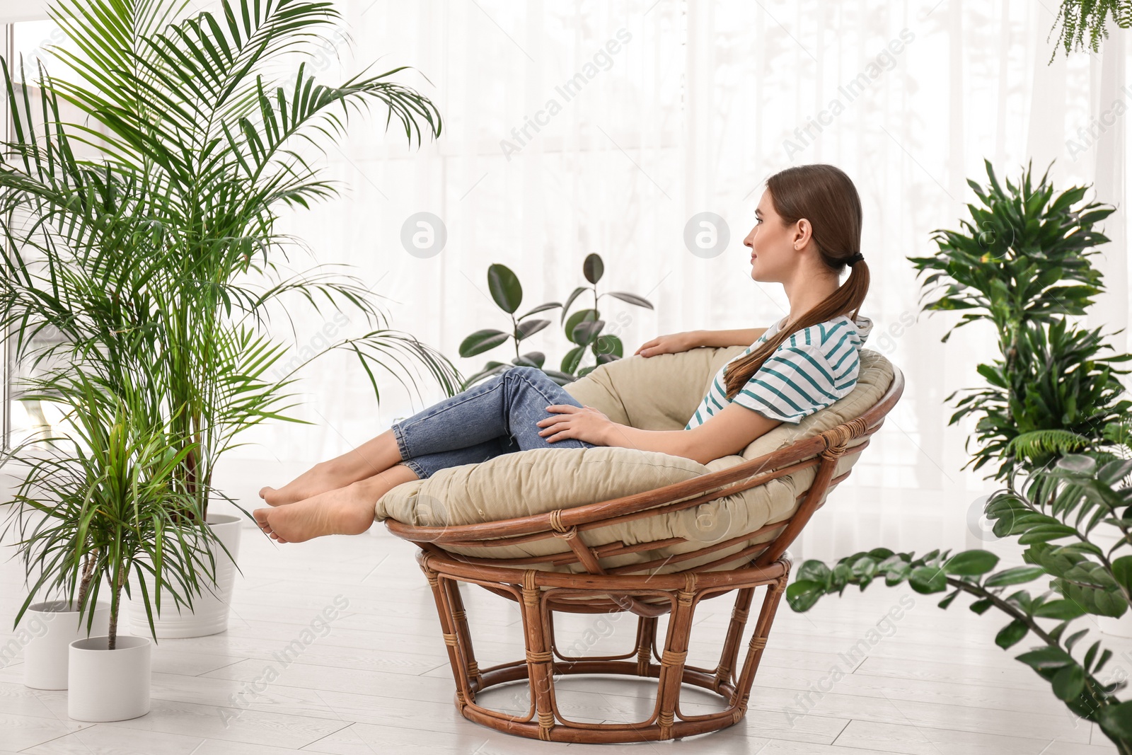 Photo of Young woman in room decorated with plants. Home design