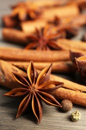 Photo of Aromatic anise stars, pepper and cinnamon sticks on wooden table
