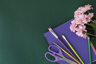 Photo of Different school stationery and beautiful pink flowers on green chalkboard, flat lay with space for text. Happy Teacher's Day