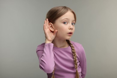 Little girl with hearing problem on grey background