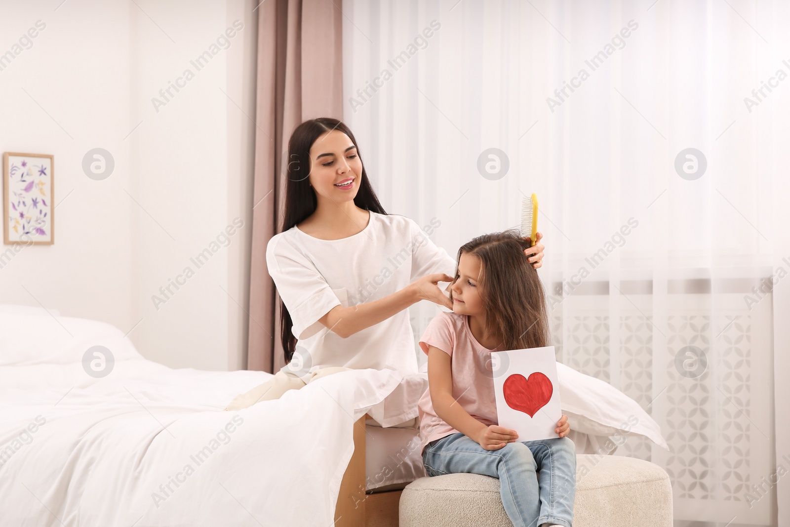 Photo of Happy woman and her daughter spending time together on bed at home, space for text. Mother's day celebration