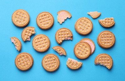 Photo of Tasty sandwich cookies with cream on light blue background, flat lay