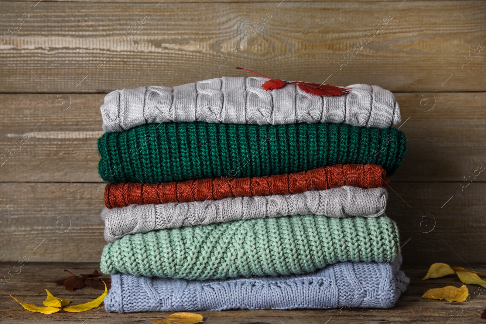 Photo of Stack of sweaters on wooden background. Autumn clothes