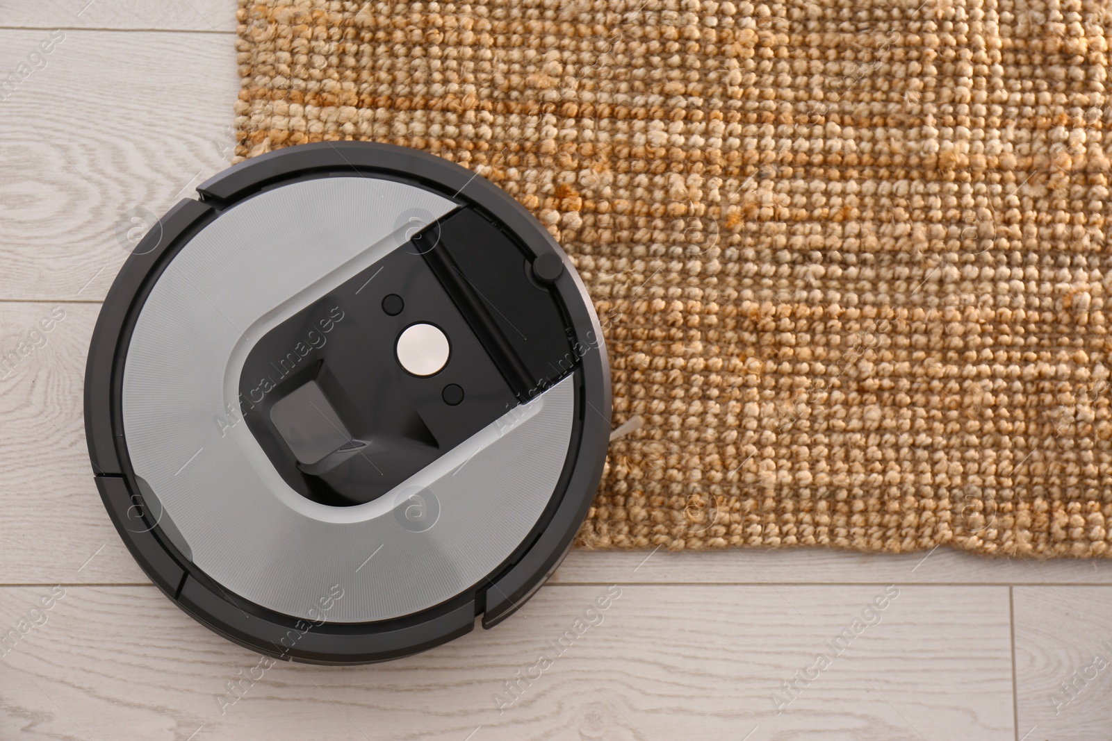 Photo of Modern robotic vacuum cleaner on brown rug, top view. Space for text