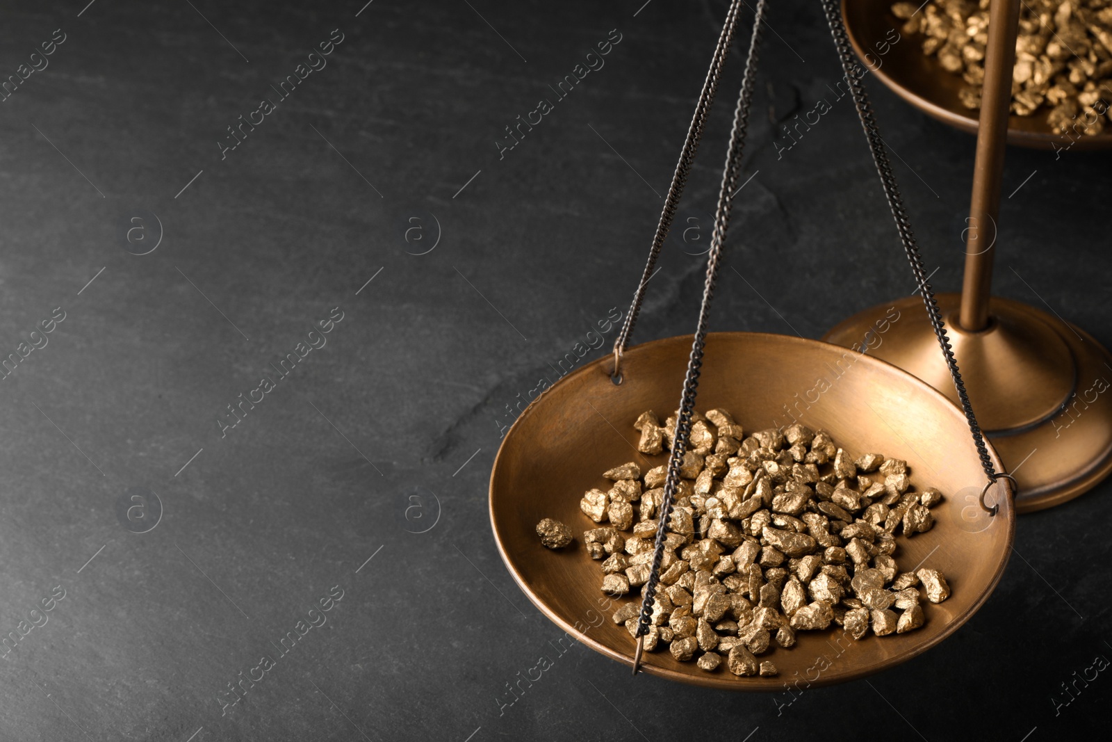 Photo of Vintage scales with gold nuggets on dark table, space for text