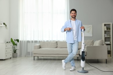 Photo of Happy man with steam mop at home. Space for text