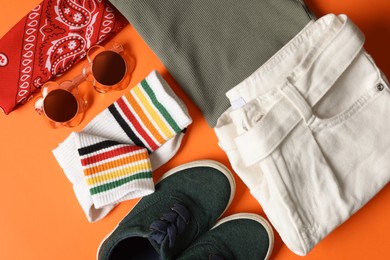 Photo of Stylish child clothes, shoes and accessories on orange background, flat lay