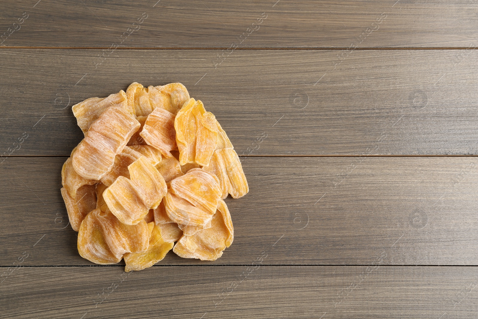 Photo of Delicious dried jackfruit slices on wooden table, top view. Space for text