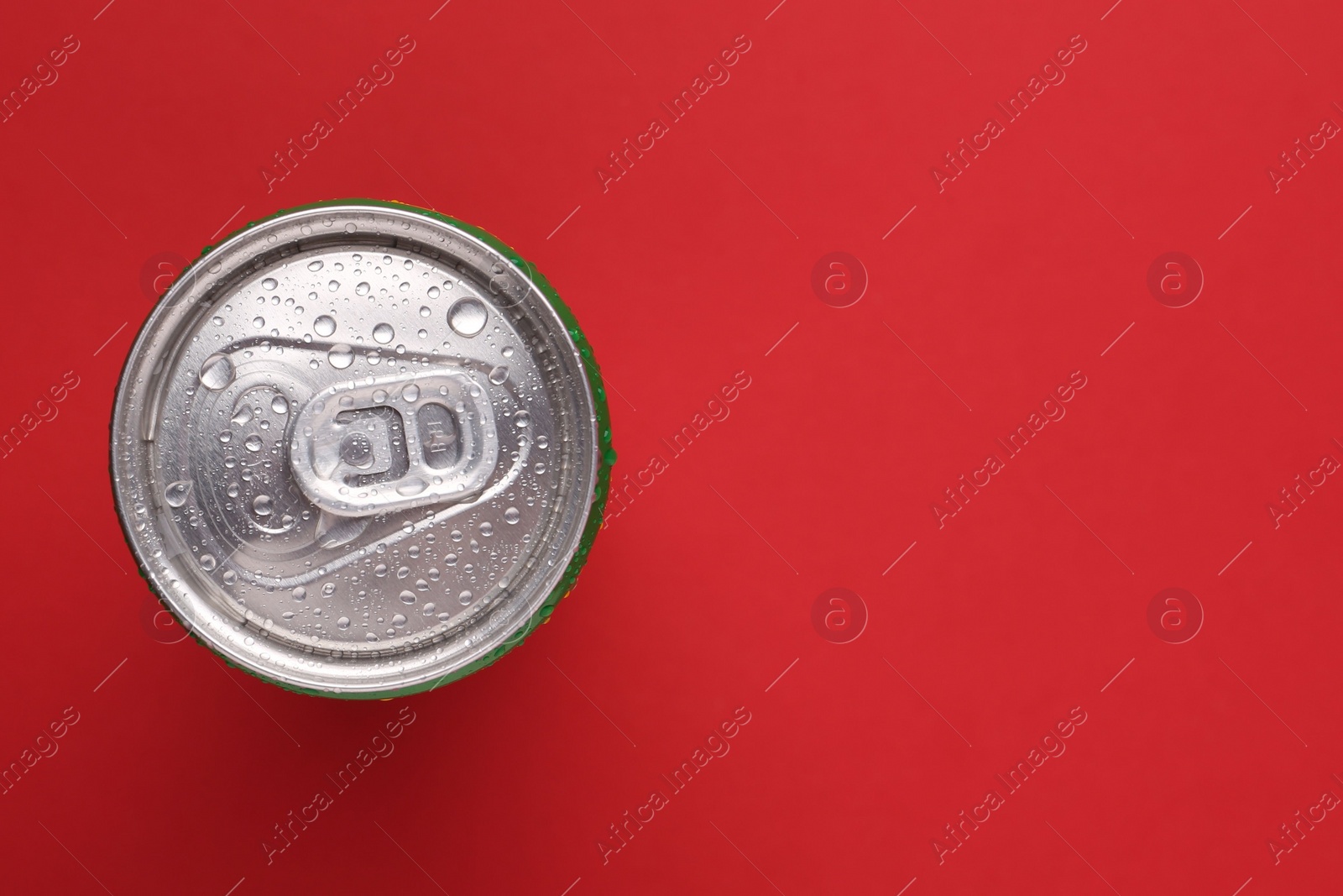 Photo of Energy drink in wet can on red background, top view. Space for text