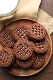 Photo of Tasty chocolate sandwich cookies with cream on wooden table, top view