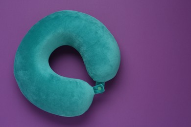 Photo of Turquoise travel pillow on purple background, top view. Space for text