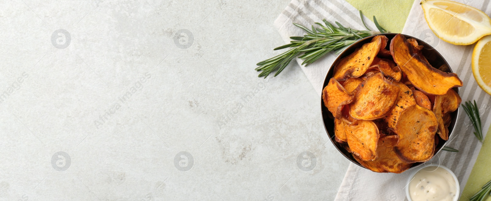 Image of Bowl of sweet potato chips and lemon on light grey table, flat lay with space for text. Banner design