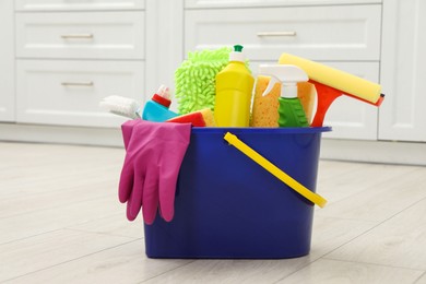 Different cleaning supplies in bucket on floor