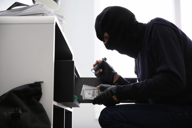 Photo of Thief taking money out of steel safe indoors