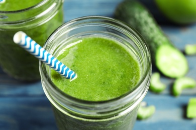 Delicious fresh green juice with straw in glass, closeup