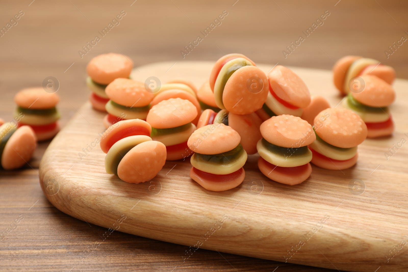 Photo of Delicious gummy burger shaped candies on wooden table, closeup