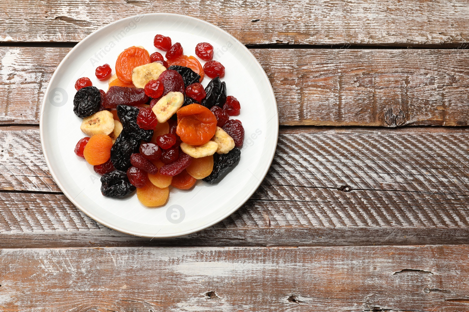 Photo of Mix of delicious dried fruits on wooden table, top view. Space for text