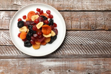 Photo of Mix of delicious dried fruits on wooden table, top view. Space for text