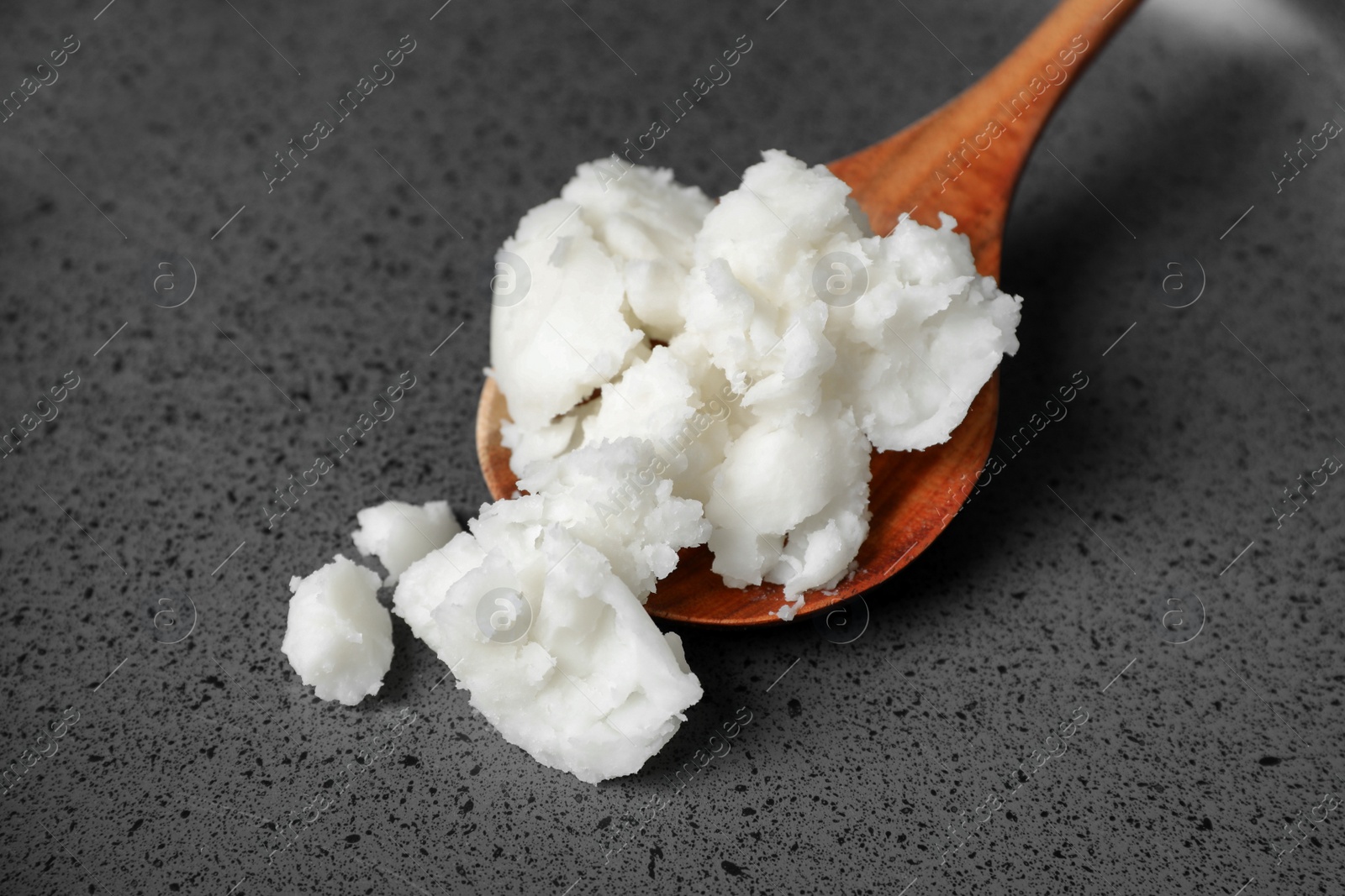 Photo of Frying pan with coconut oil and wooden spoon, closeup